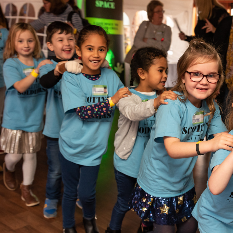 Bereaved British Forces children and young people in a conga line at Scotty's Little Soldiers Christmas Party