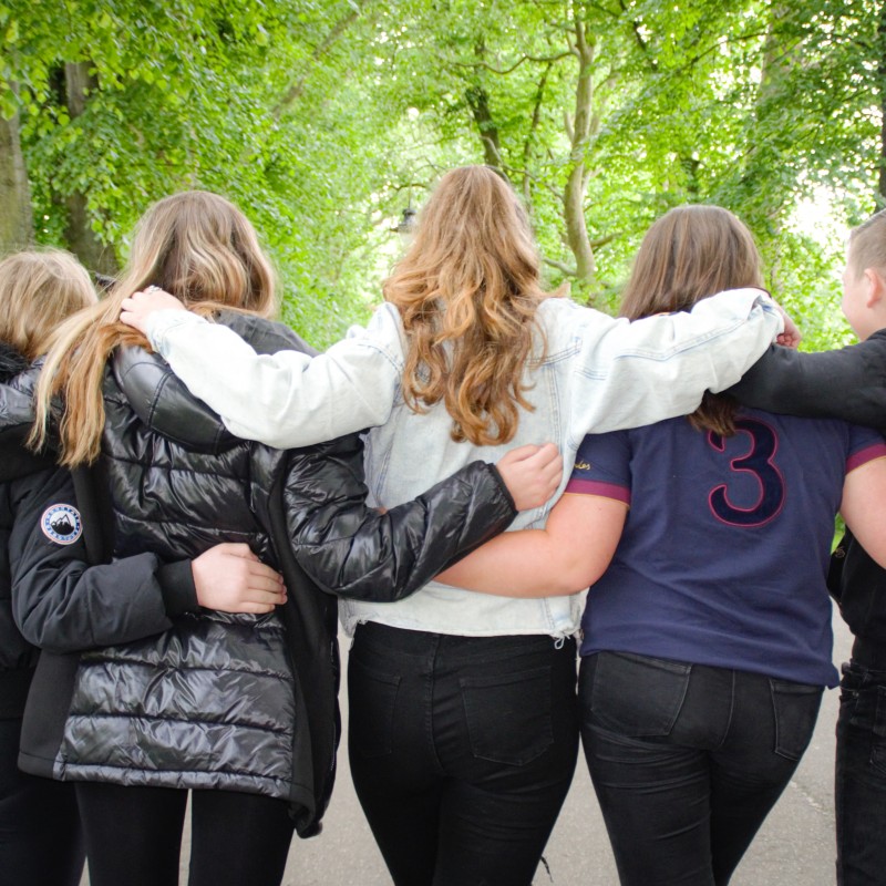 Group of bereaved military children and young people with arms around each other in park